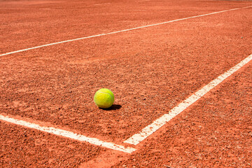 A tennis ball on a dirt court. bright sunny day. vivid colors