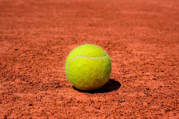 A tennis ball on a dirt court. bright sunny day. vivid colors