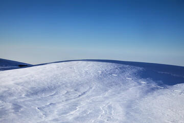 Obraz premium Landscape of snowy hill in the mountains and blue sky