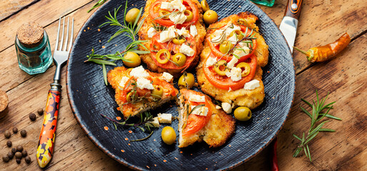 Meat schnitzel with cheese, olives and tomato