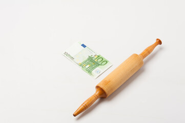 Images on the topic of world economics and finance. Allegory of financial cuisine. Rolling pin and one hundred euro banknote on a white background.