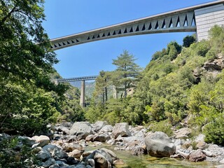 Modern road bridge and old Gustave Eiffel railway bridge over Vecchio river in Vivario, Corsica.