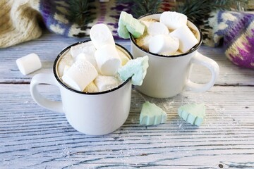 Merry Christmas, cups of coffee with marshmallows, fir branches, New Year's toys and illumination on a light wooden background