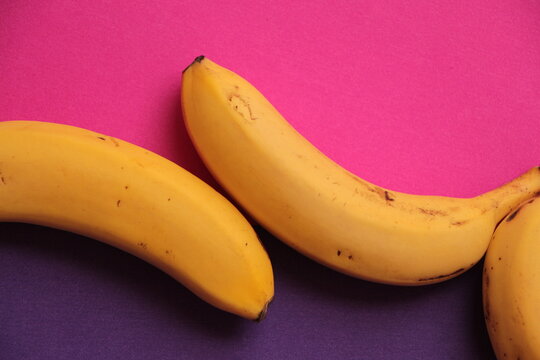 Banana. Purple and pink background. Creative fruit photo. Three Bananas. Delicious ripe bananas with black spots
