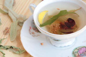Herbal tea in the porcelain tea cup. Linden, rosehip(dog rose) and lemon balm(natural melissa) tea with lemon. Healthy lifestyle.