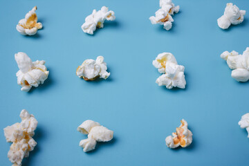 Obraz na płótnie Canvas Popcorn lay out on blue background, close up shot. Food pattern