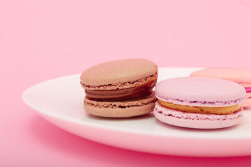 three macaroons on white plate on pink paper background. Sweet bakery, copy space. Overweight, diet, diabetes, healthy eating habits.