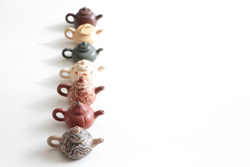 Small decorative teapots. Brown, beige, tile and green color teapots. Tea pots in a row. Chinese traditional clay teapot on the whitee ground. Copy space for text and list.