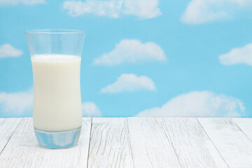 Cold glass of milk on weathered wood with clear sky