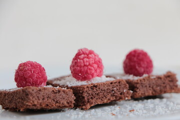 Raspberry and coconut zest on three pieces of chocolate cake.  Brownie	