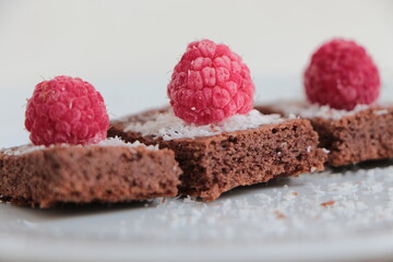 Raspberry and coconut zest on three pieces of chocolate cake.  Brownie	