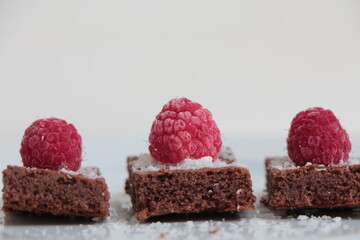 Raspberry and coconut zest on three pieces of chocolate cake.  Brownie	