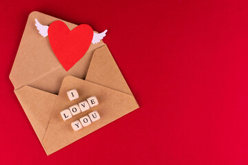 Envelope and heart with wings on a red background.Copy space.