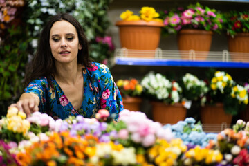 Beauty woman in a florist store picking up a some flowers