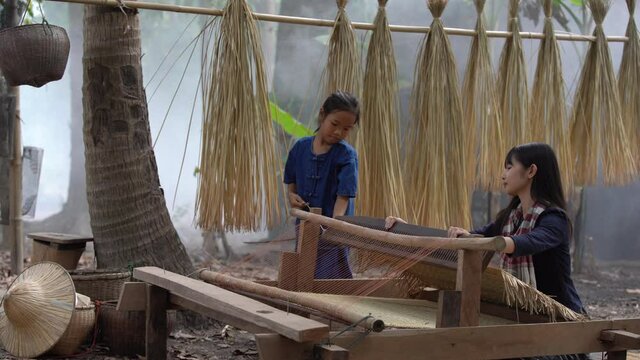 Asian girl is weaving the mat. Girl weaving mats in the countryside. Nong Khai, Thailand.