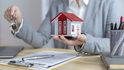 Sales manager or salesperson holds a demo house and has a home purchase contract with keys to...
