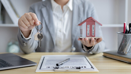 Sales manager or salesperson holds a demo house and has a home purchase contract with keys to...