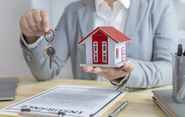 Sales manager or salesperson holds a demo house and has a home purchase contract with keys to...