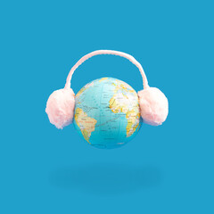 Ear heaters are placed on the floating globe. Creative idea, on a blue background.