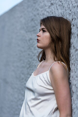 Fototapeta premium Close-up portrait of a pretty young white woman, standings against a rough wall