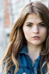Fototapeta premium Close-up portrait of a pretty young white woman, standings against a rough wall