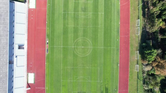 DRONE AERIAL FOOTAGE: The Manuela Machado Municipal Stadium, in Viana do Castelo, Portugal. Empty red running sports tartan track synthetic rubber on the athletic stadium.