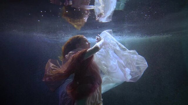 underwater magical nymph is floating in river or lake, romantic female figure in water