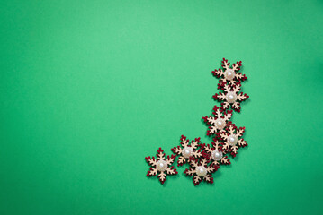 A toy festive snowflakes on the green flat lay background with copy space.