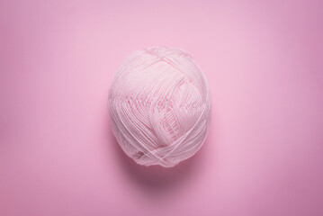 Pink woolen thread on the pink flat lay background. Knitting abstract background.