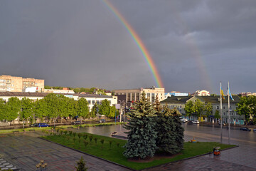 Urban landscape with big rainbow in the scenic sky