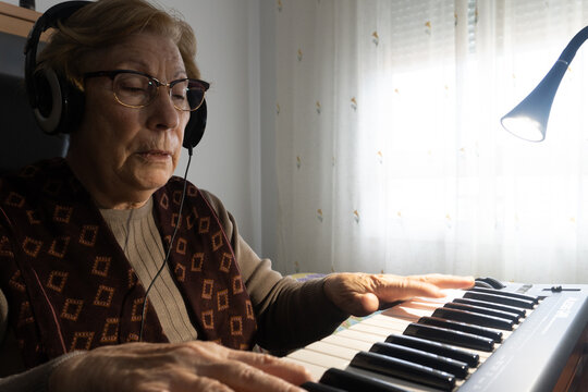 Caucasian Elderly Woman Learning Music And Playing The Musical Keyboard.