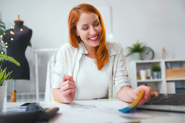 Smiling young entrepreneur woman working in her fashion design studio