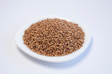 Buckwheat in a white plate on a white background. Healthy food. Cereals