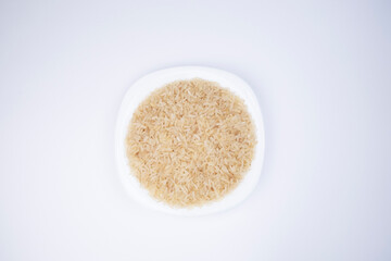 Rice. Rice in a white plate on a white background, top view. Selection of rice for meals. Choosing rice for sushi. Healthy grains. Healthy food.