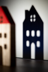 Toy house shadow on white wall. Defocused small home building with red roof. Fairytale for kids,...