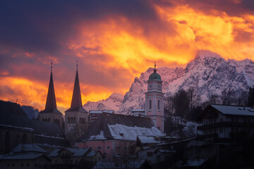 Berchtesgaden fiery sunset. Burning sky over the church towers of Berchtesgaden and Mount Hochkalter on a cold, snowy winter day.