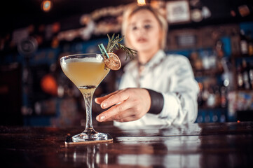 Young girl mixologist is pouring a drink in the nightclub