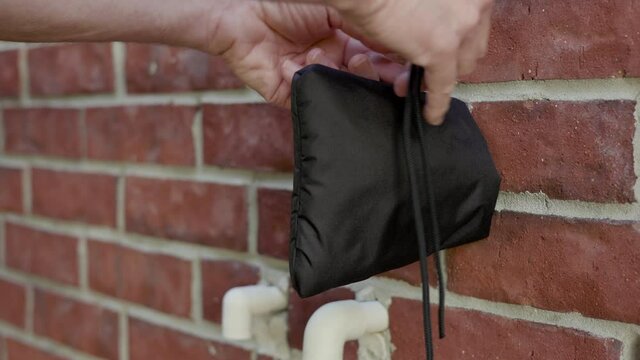 A homeowner winterizing a faucet using an insulated slip on cover.