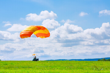 The parachutist successfully landed on the green grass. Air sports and entertainment.