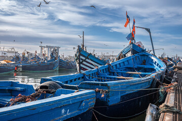 Essaouira, Morocco. October 10, 2021. Small fishing boats moored on coast at port against cloudy...