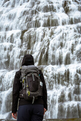 Backpacker enjoying the view of majestic Dynjandi waterfall, largest waterfall in Westfjords - Iceland