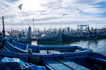 Essaouira, Morocco. October 10, 2021. Small fishing boats moored on coast at port against cloudy...