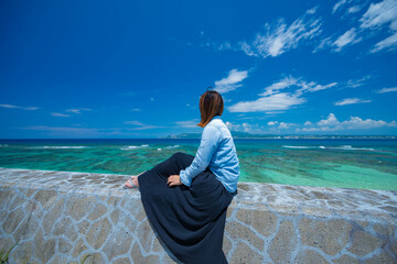沖縄の青い海を座って見つめる女性①