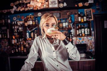 Focused barmaid demonstrates the process of making a cocktail at the night club