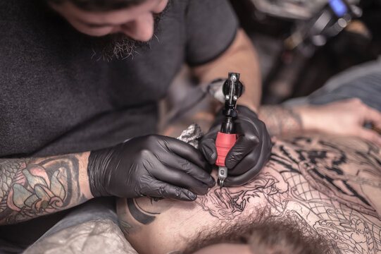 Tattooer makes tattoo in salon