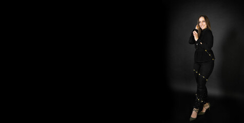 The girl is wrapped in garlands. Portrait on a background of black cyclorama. Copy space for text or signature.