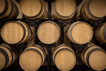 Oak barrels stacked for wine aging in winery vault