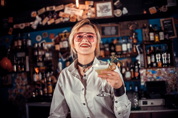 Confident woman barman formulates a cocktail in cocktail bars