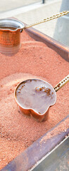 Cooking Turkish traditional hot coffee in the sand and a cezve. Batumi, Georgia