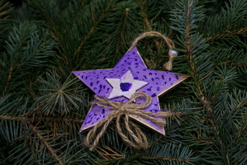 Christmas toy, decorated wooden star, on the branches of a Christmas tree, photo indoors with light